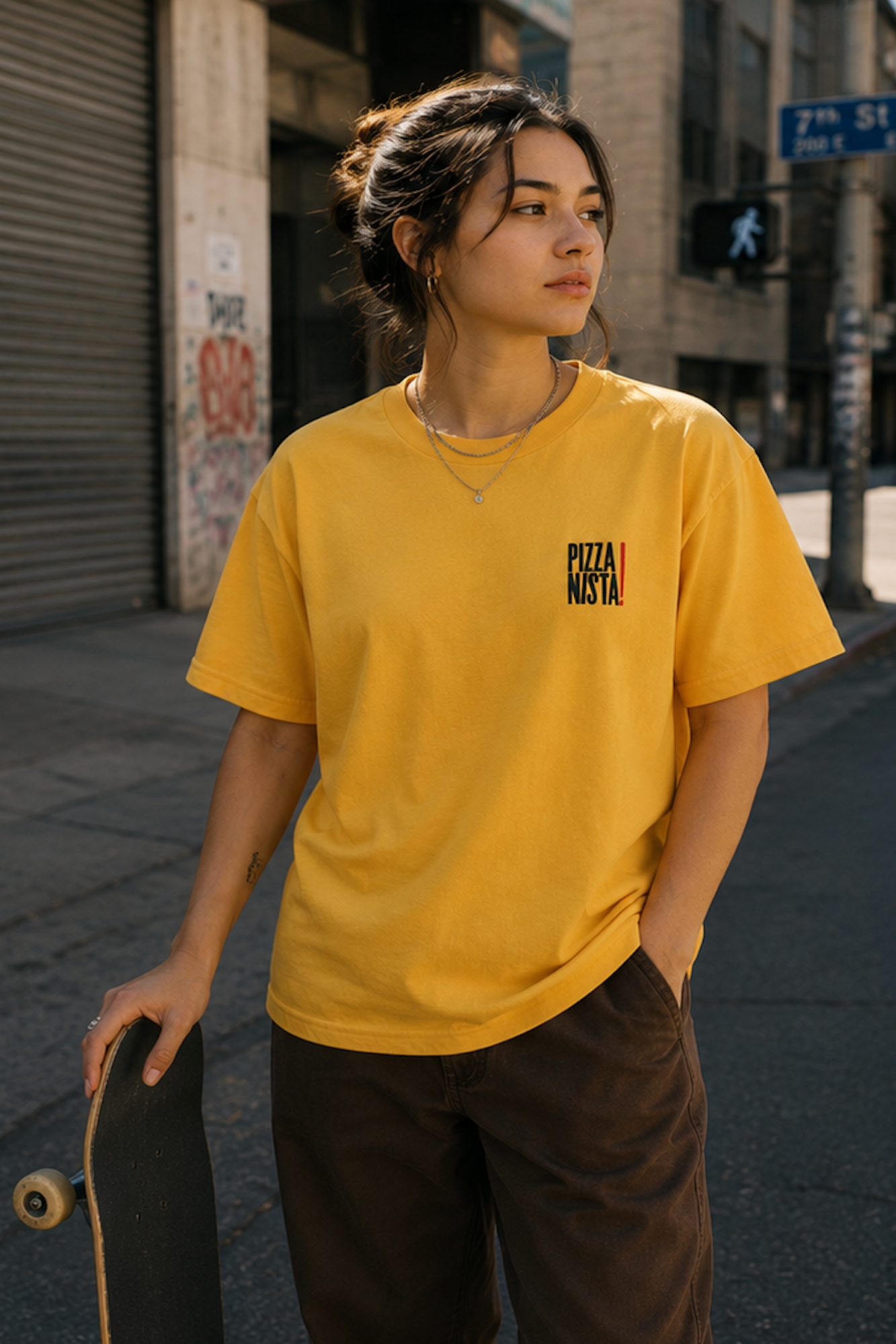 A female skateboarder modeling PIZZANISTA! BASIC BLADE SIGN LOGO TEE in Downtown Los Angeles. 